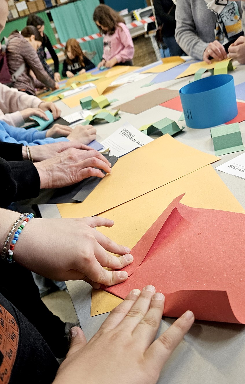 particolare mani che piegano origami in carta riciclata